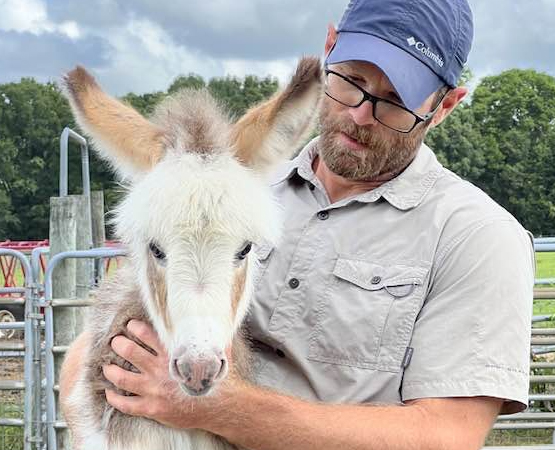 Mike and a cute white and tan miniature donkey